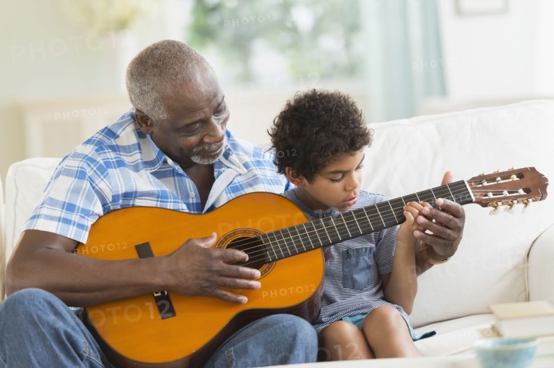 Boy playing guitar with grandfather