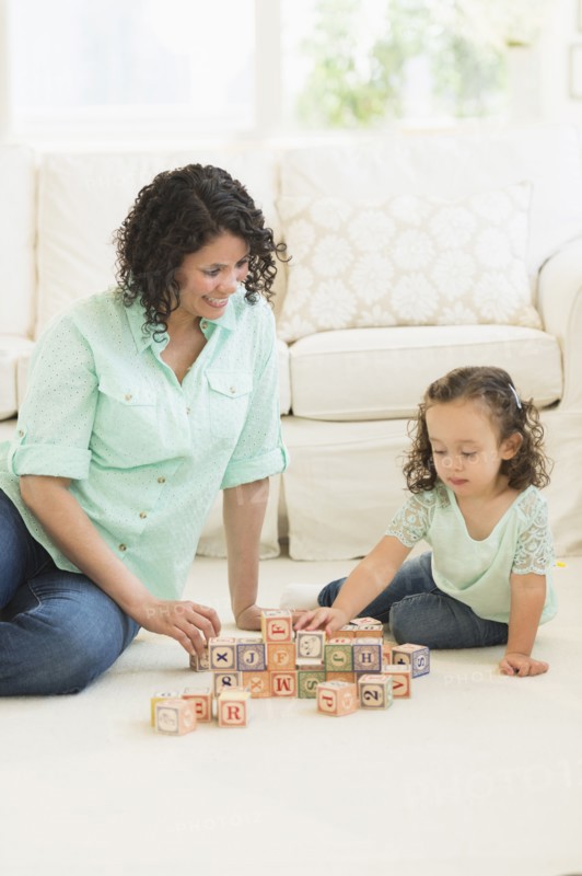 Mixed race mother and daughter playing with wooden blocks