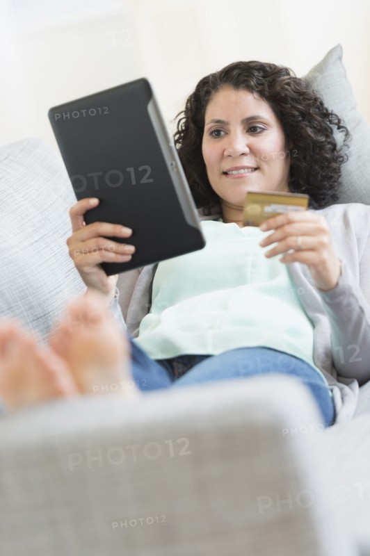 Hispanic woman using digital tablet on sofa