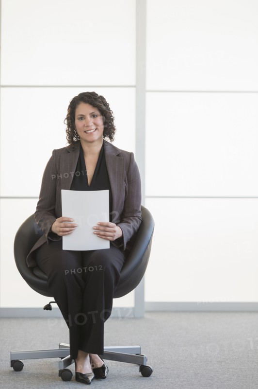 Hispanic businesswoman sitting in office chair