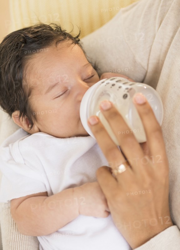 Hispanic mother feeding newborn baby