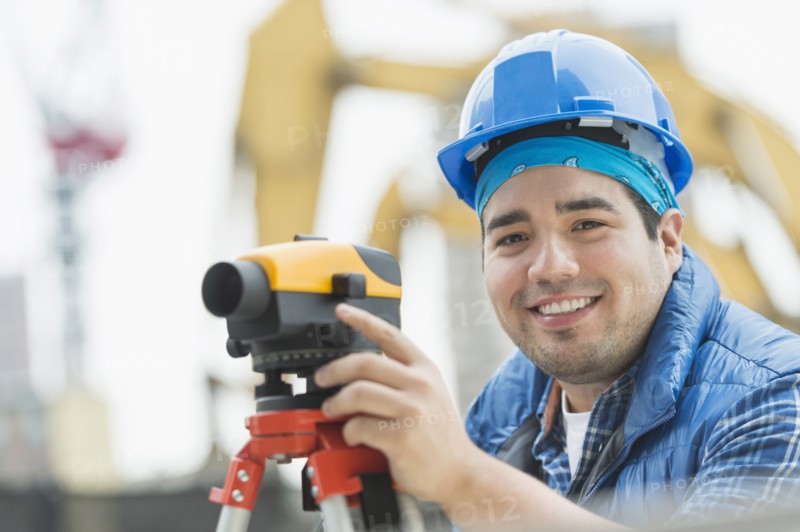 Mixed race engineer using theodolite at construction site