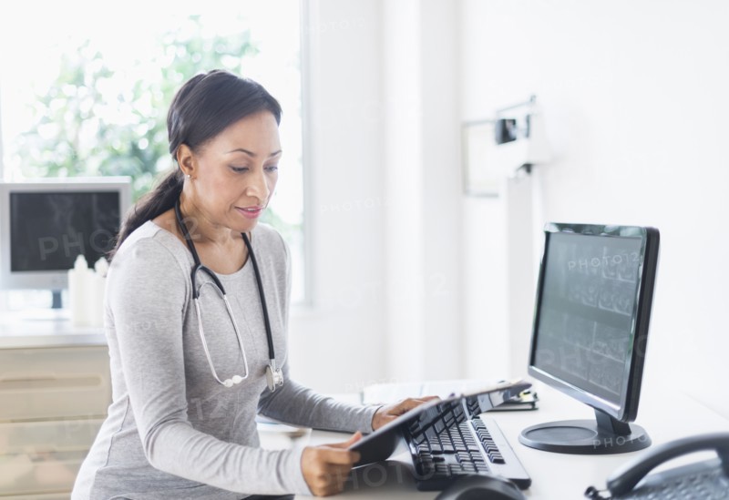 African American doctor looking down at clipboard