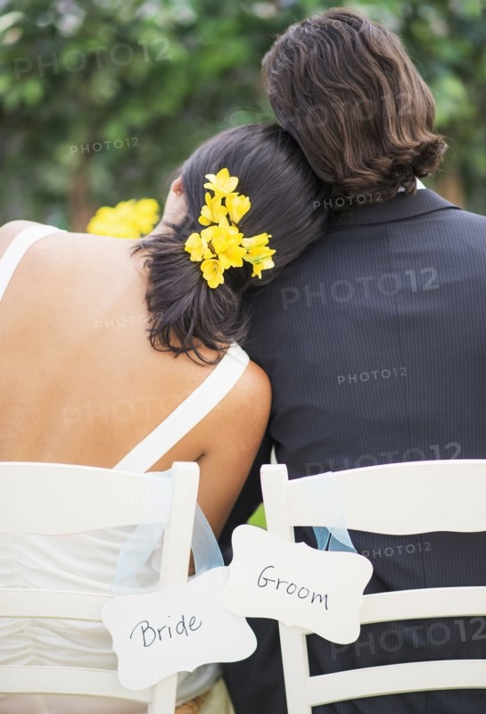 Newlywed couple sitting at wedding reception outdoors