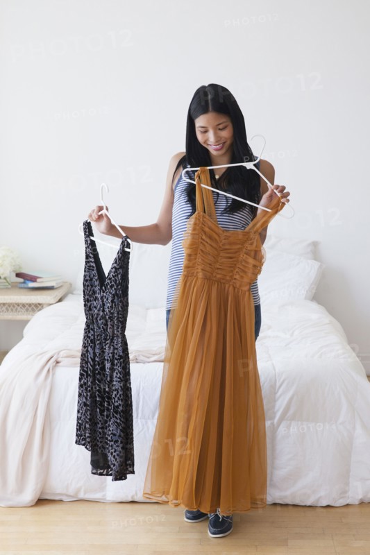 Chinese woman picking out dresses in bedroom