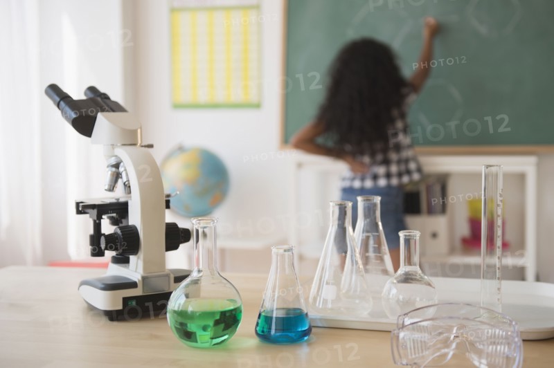 Mixed race student writing on chalkboard in classroom