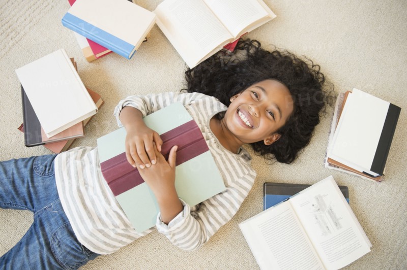 Mixed race girl laying on floor with books
