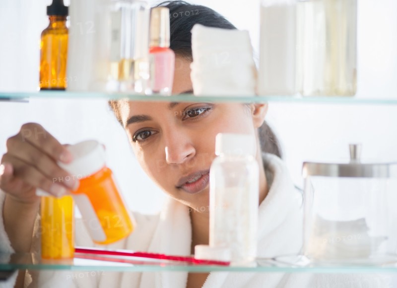 Close up of Asian woman examining label of prescription bottle