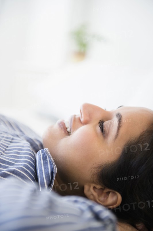 Close up of serene Asian woman laying with hands behind head