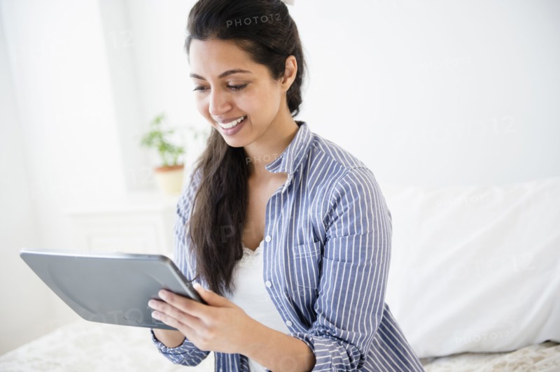 Asian woman using digital tablet in bedroom