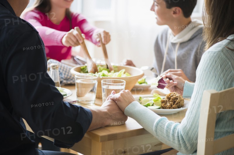 Caucasian parents holding hands at table