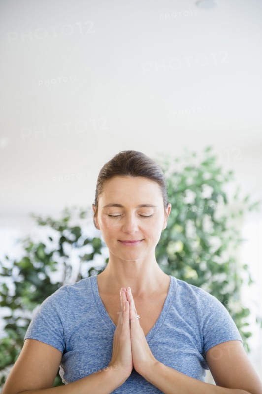 Serene Caucasian woman with hands in prayer position