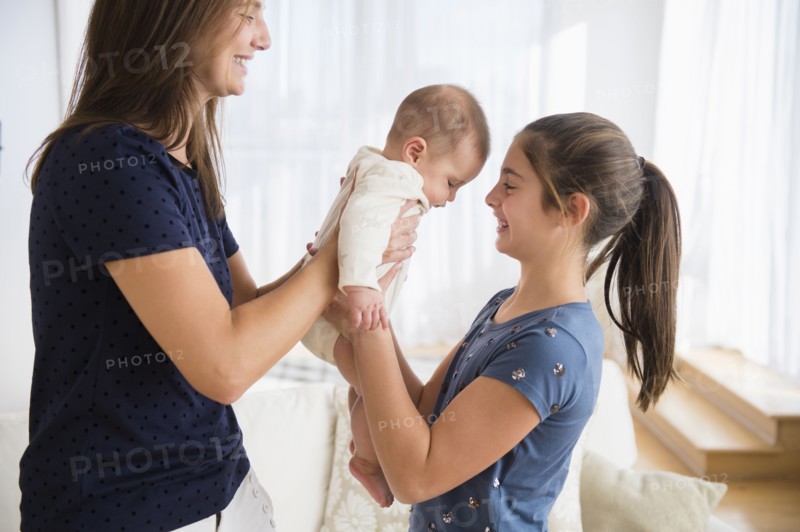 Caucasian mother handing baby girl to daughter