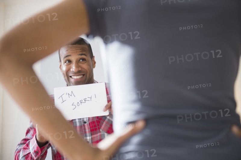 Man showing 'I'm Sorry' sign to angry girlfriend