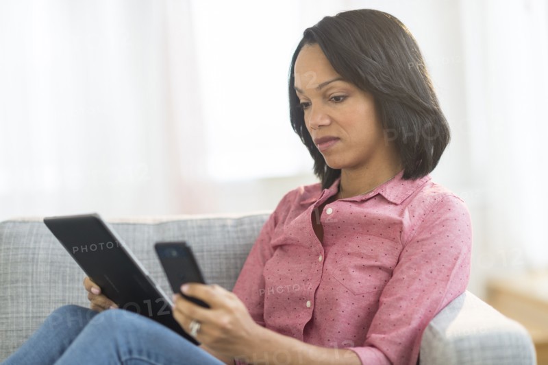 African American woman using cell phone and digital tablet