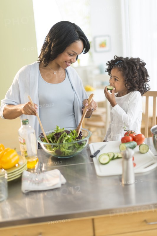 African American mother and daughter tossing salad