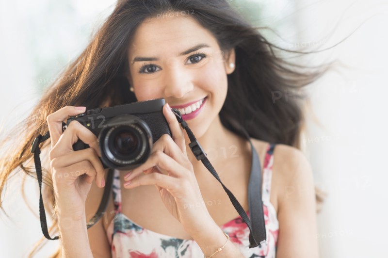 Portrait of smiling Hispanic woman holding digital camera