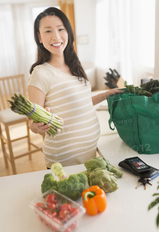 Portrait of pregnant Japanese woman unloading groceries