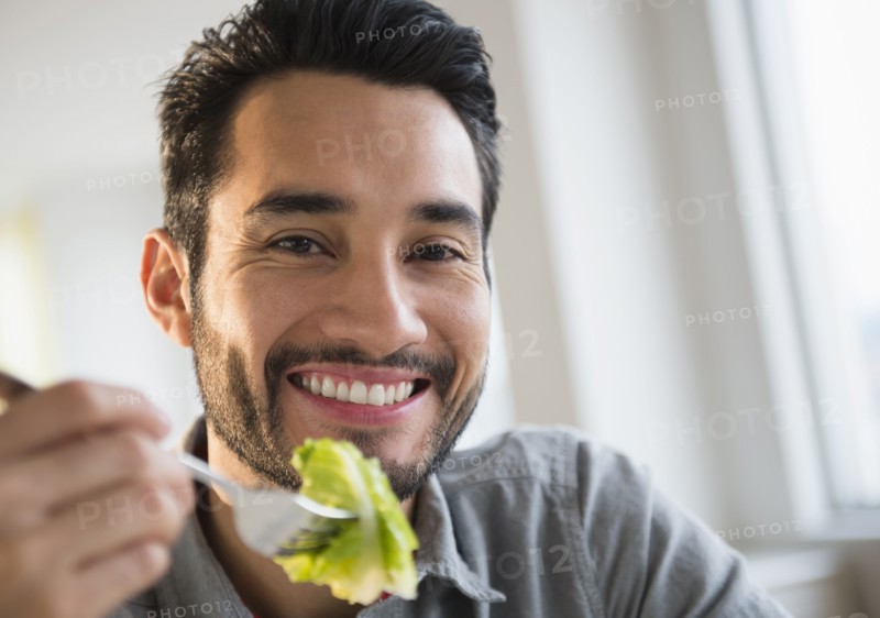 Mixed race man eating salad