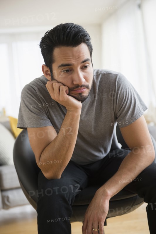 Mixed race man resting chin in hand