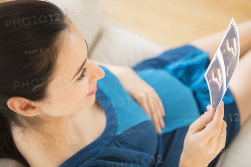 Pregnant Caucasian woman examining ultrasounds