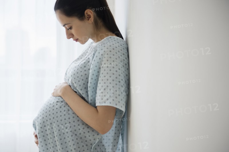 Pregnant Caucasian woman holding her belly in hospital