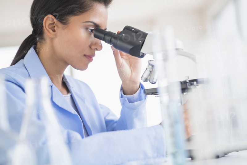 Hispanic scientist using microscope in laboratory