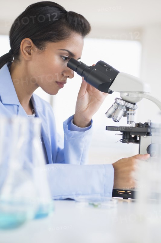 Hispanic scientist using microscope in laboratory