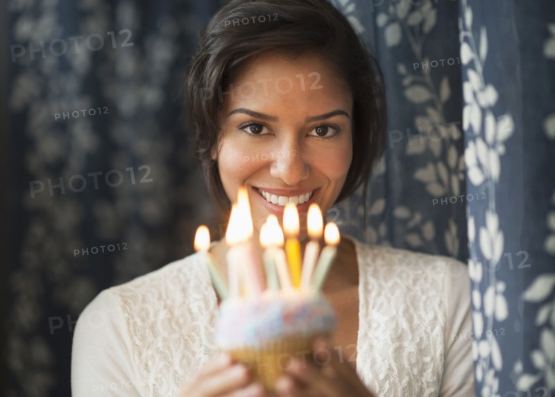 Hispanic woman holding birthday cupcake