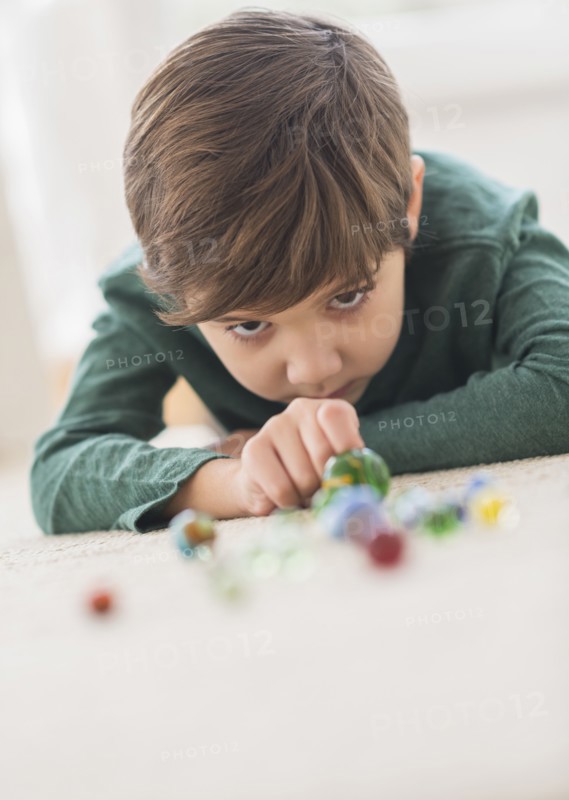 Hispanic boy playing with marbles on floor