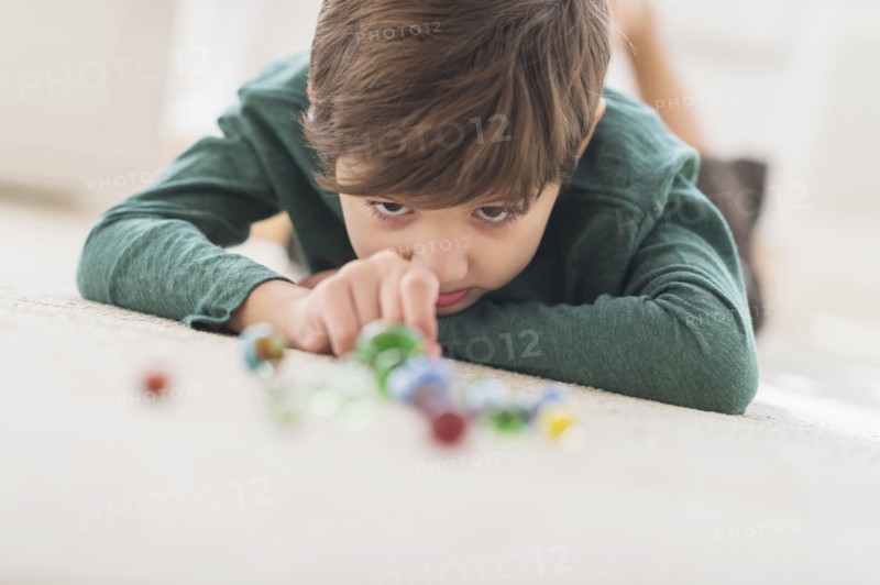 Hispanic boy playing with marbles on bedroom floor