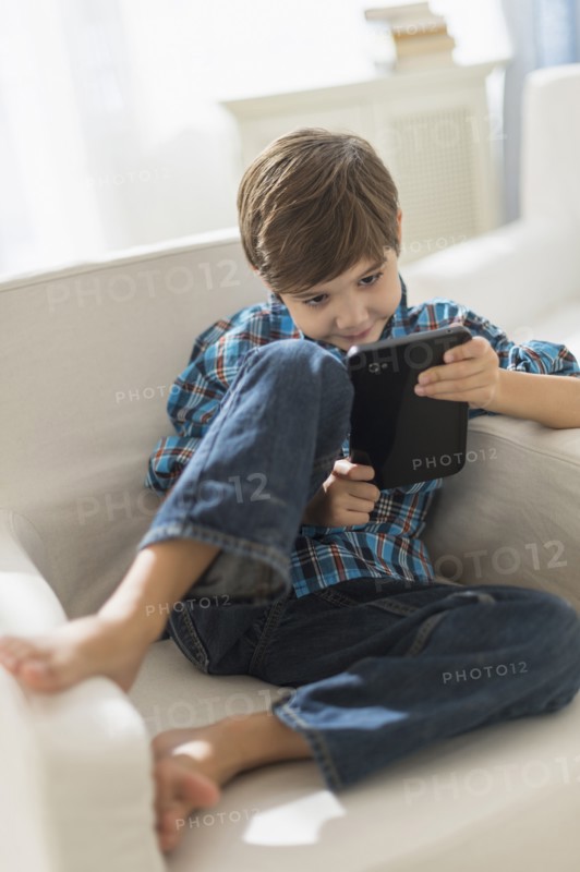 Hispanic boy using digital tablet in armchair