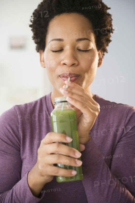Close up of Black woman drinking green smoothie