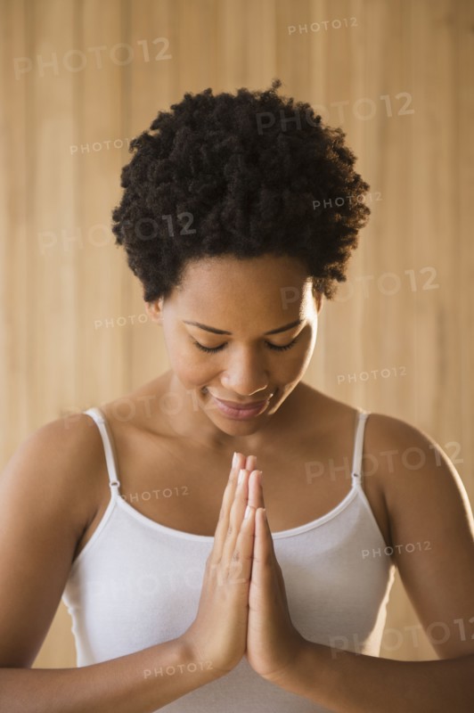 Close up of serene Black woman with hands in prayer position