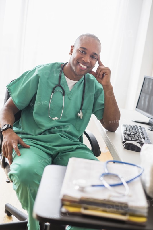 Black doctor smiling at computer in office
