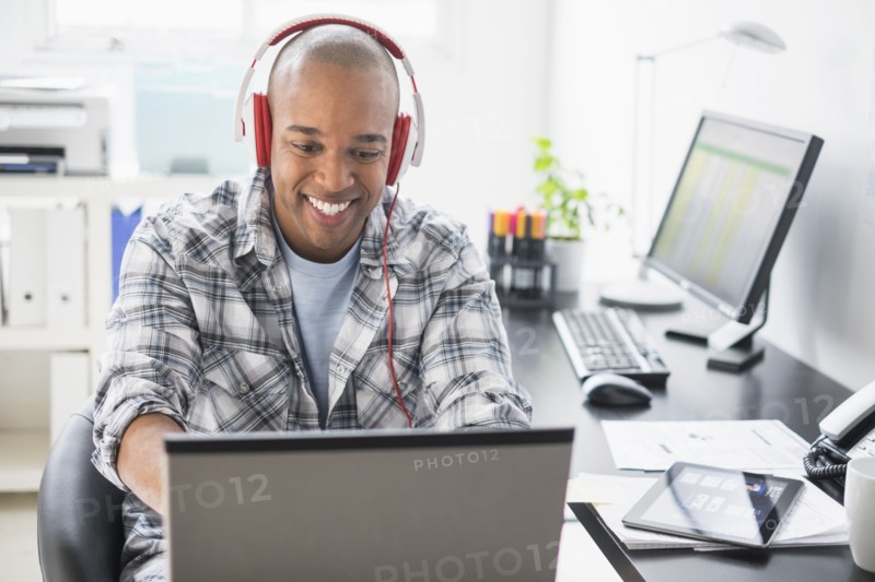 Black businessman listening to headphones in office