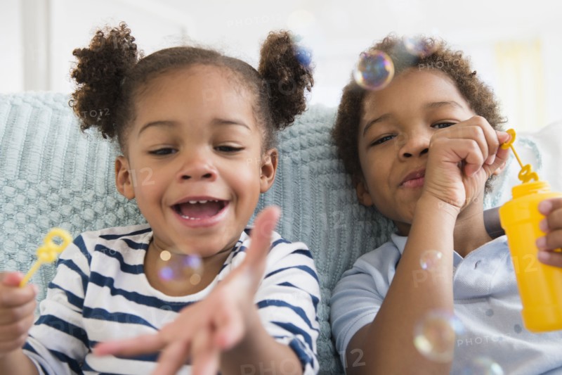 Black children blowing bubbles together