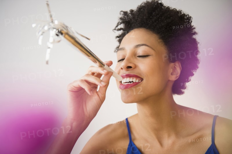 Black woman blowing noisemaker at party