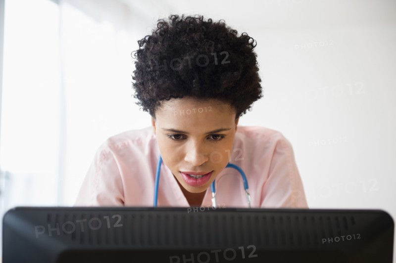 Black nurse working on computer in office