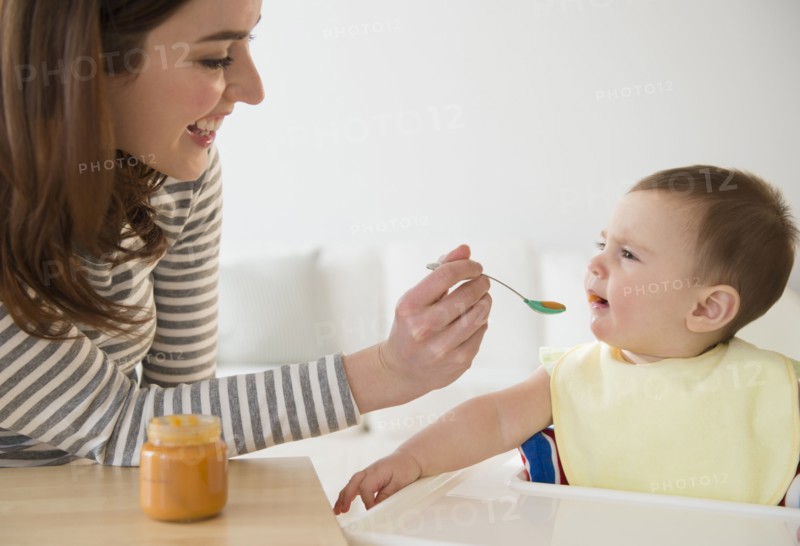 Mother feeding baby in high chair