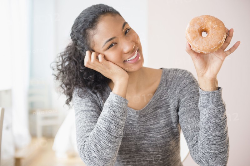 Mixed race woman holding donut