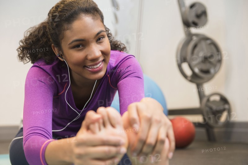 Mixed race woman stretching in gym