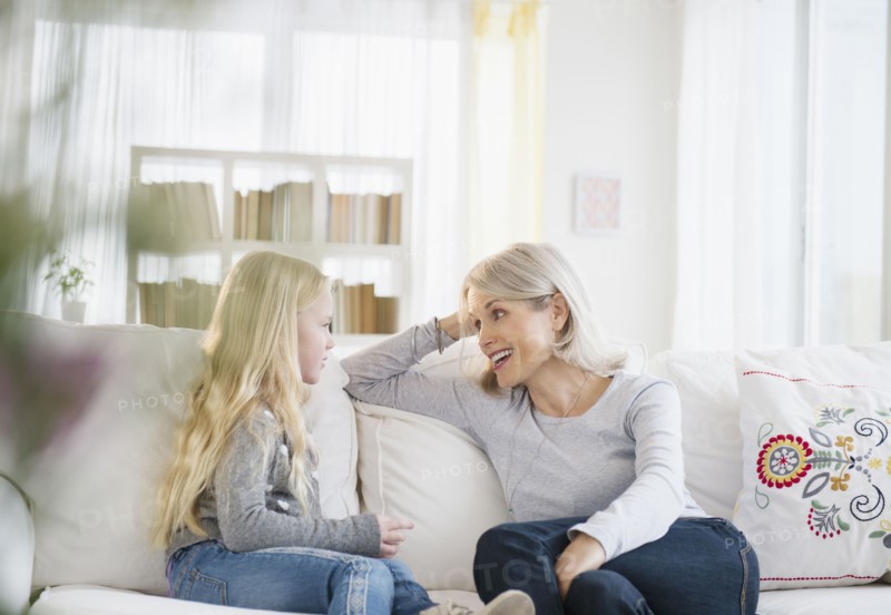 Senior Caucasian woman and granddaughter talking on sofa