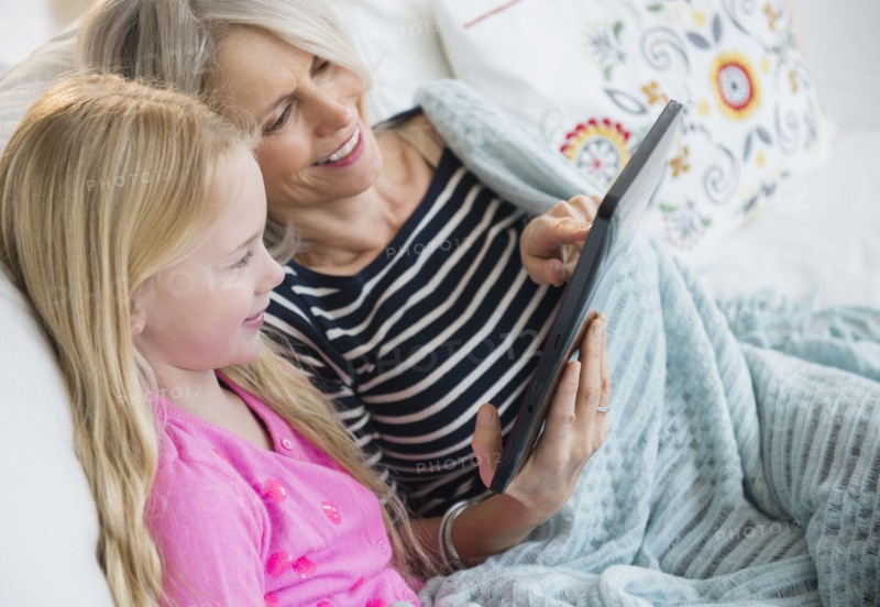 Senior Caucasian woman and granddaughter using digital tablet on sofa