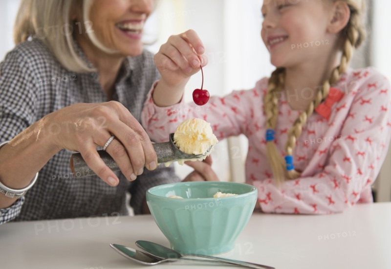 Senior Caucasian woman and granddaughter making ice cream sundae