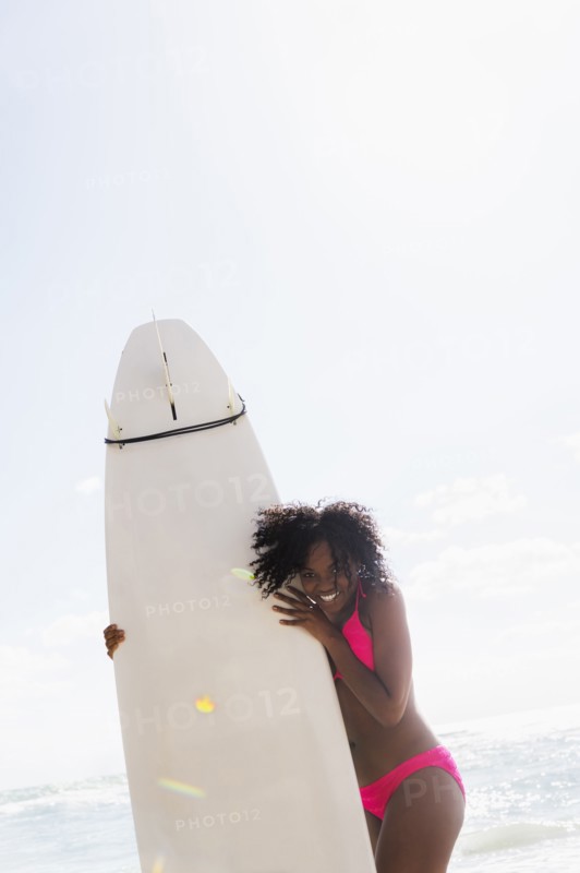 African American woman holding surfboard on beach