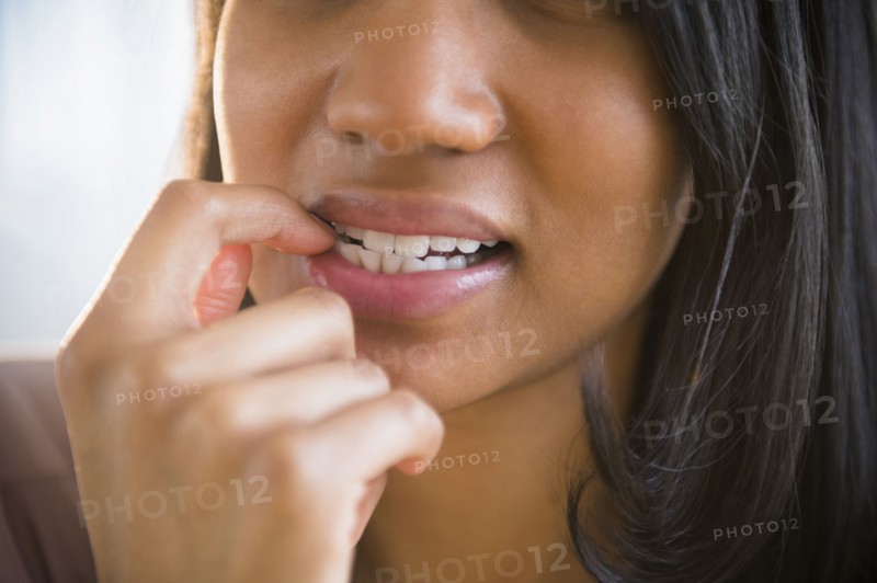 Mixed race woman biting her nail