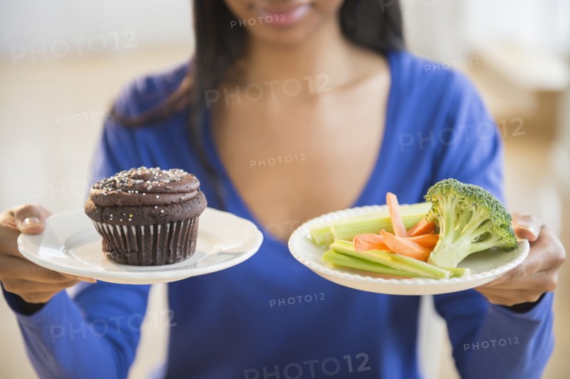 Mixed race woman choosing vegetables or cupcake
