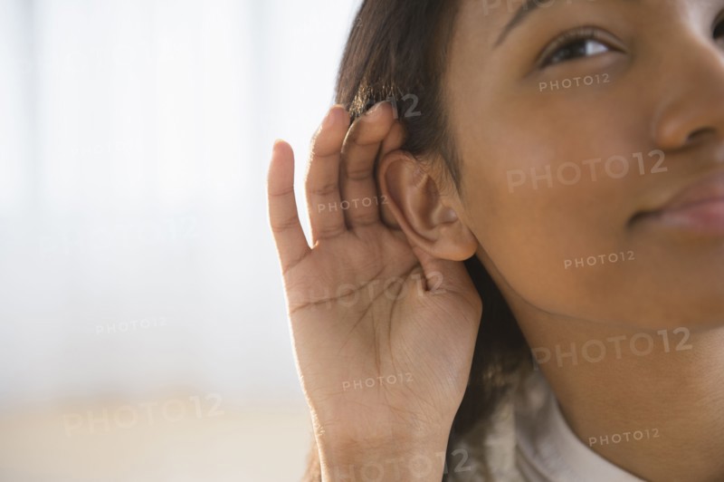 Mixed race woman cupping her ear
