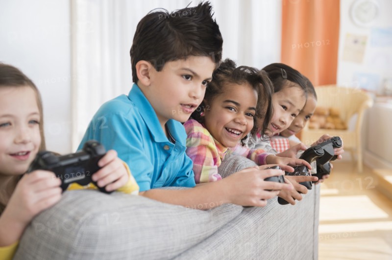 Children playing video games on sofa